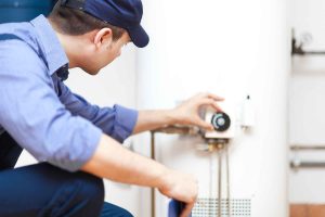 Technician performing water heater services and maintenance in a residential home